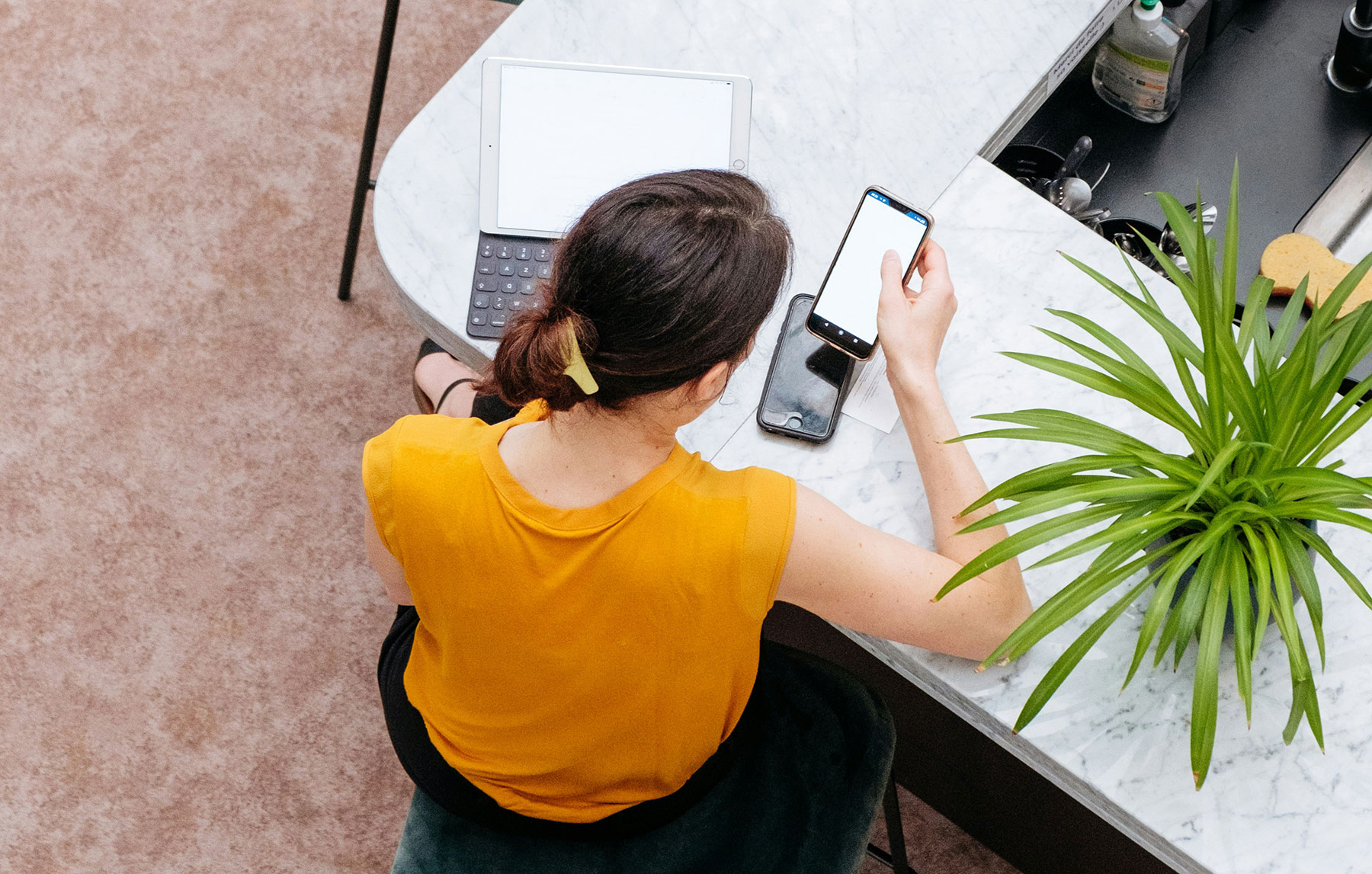 Return to Work: Woman looks at her phone and laptop screen